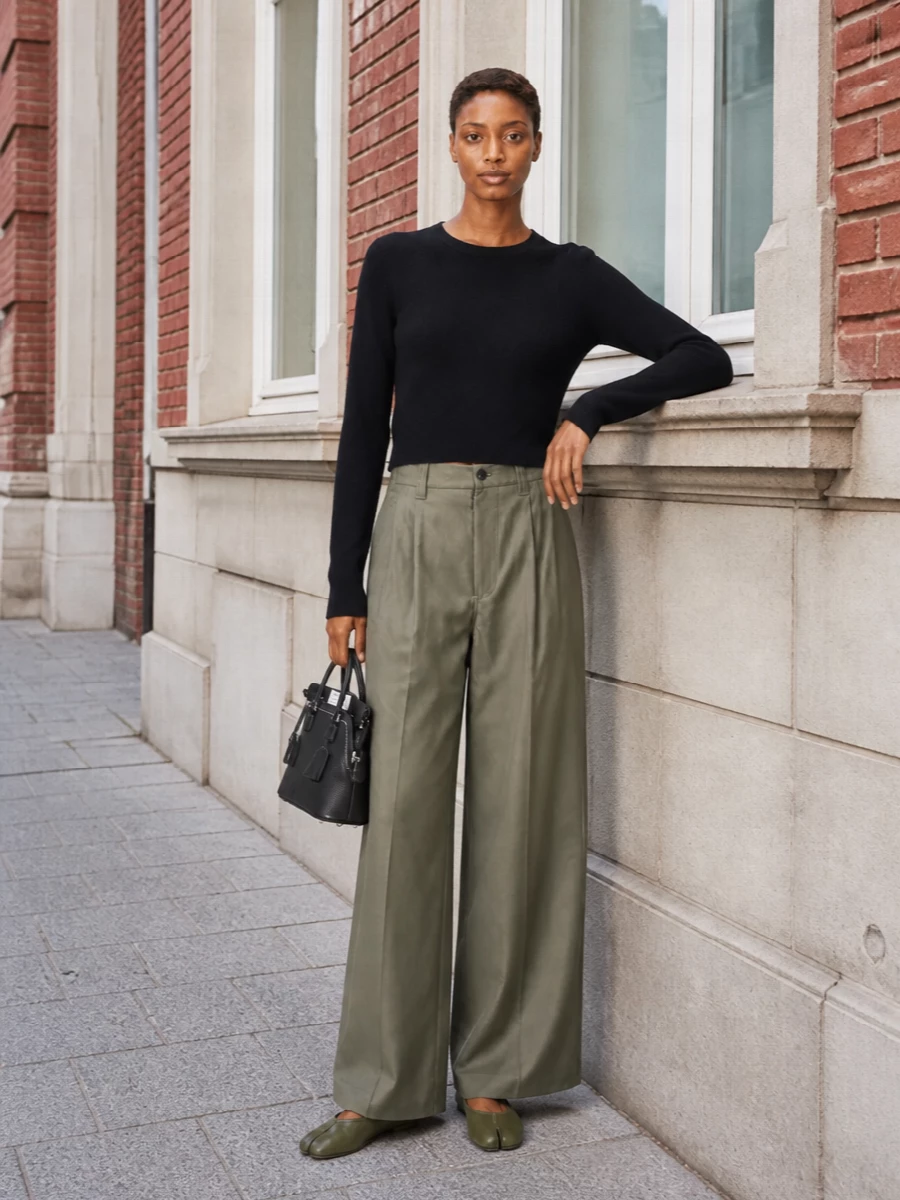 A cropped black Margiela knit meets high-rise khaki wide-leg trousers for a clean, sculptural take on city dressing that quietly echoes the Tabi’s olive tone. The wide leg lengthens the line above the low-profile flat, while the black top-handle bag sharpens the palette and keeps the mood understated and refined. I chose the top-and-trouser route over a dress to mirror the shoe’s off-duty-to-tailored versatility and keep the silhouette relaxed but precise for daytime wear.