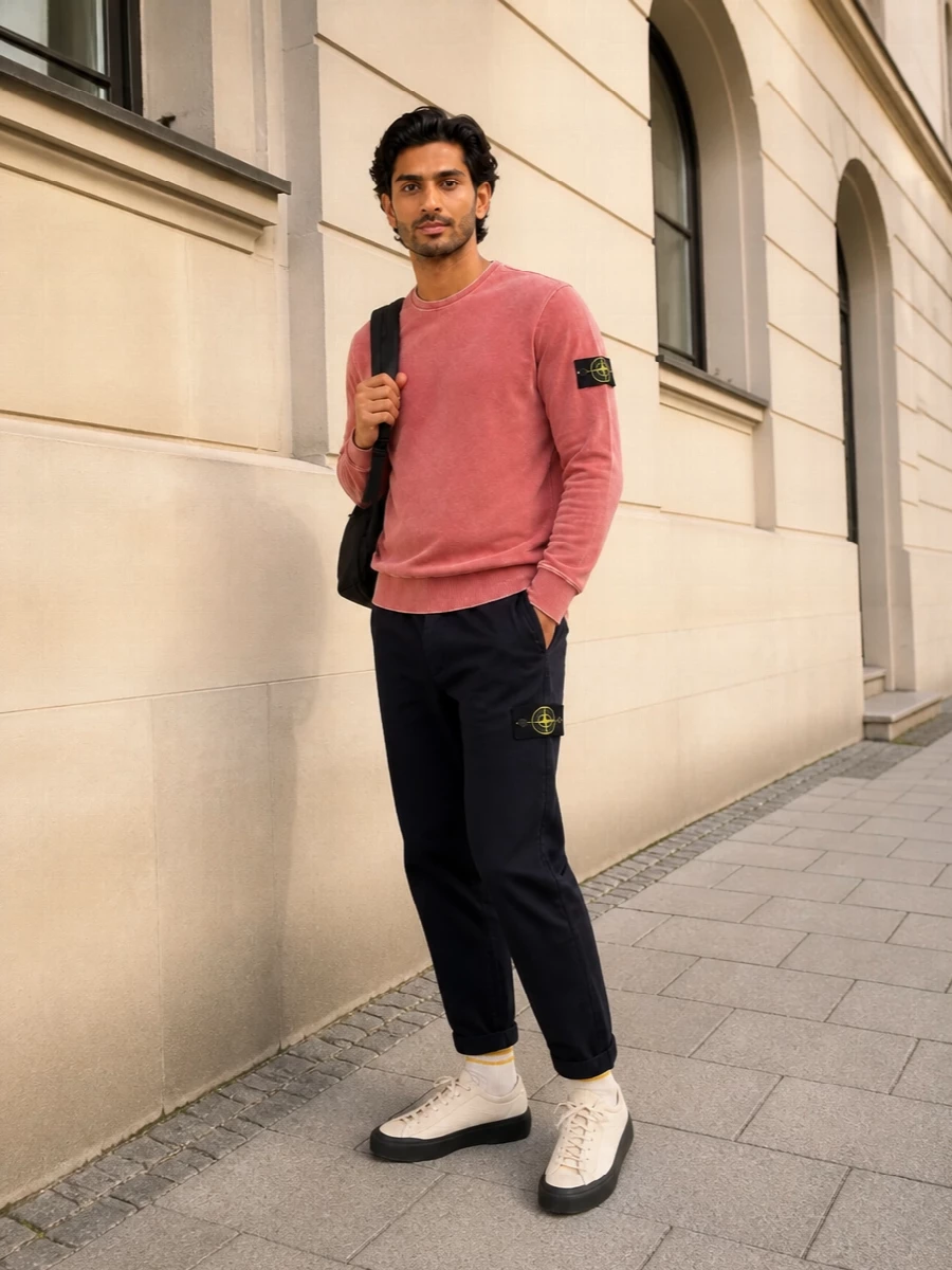 Washed coral up top is cooled down with deep navy chinos, giving a relaxed Stone Island take on city sport that still feels considered. Neutral technical sneakers and a clean black backpack keep the palette tight and functional for travel or all-day movement. The striped socks add just enough graphic detail to stop the outfit feeling flat while staying firmly in the streetwear lane.