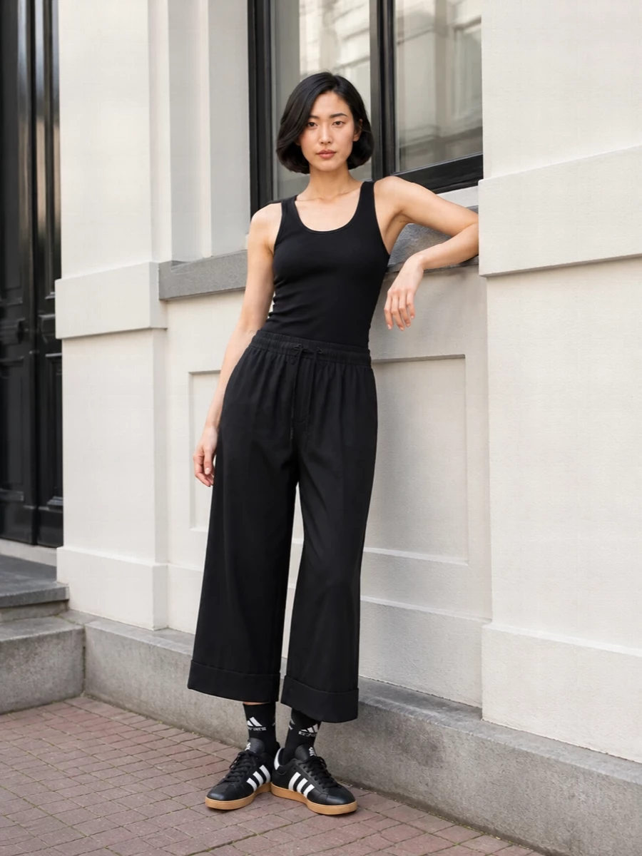 Head-to-toe black keeps this Entire Studios set feeling sharp yet easy, with the close-cut ribbed tank offsetting the volume of the cropped wide-leg pant. Low-profile Adidas sneakers and Margiela’s folded tote lean into a quiet street uniform, while logo socks add a small, intentional flash of attitude when you move.