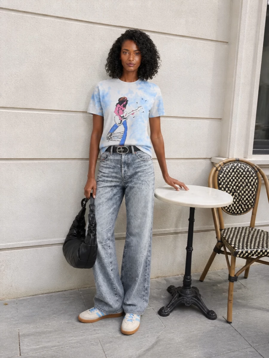 A washed sky-blue guitarist tee drops into icy wide-leg Diesel denim for a nostalgic, street-led take on band-kid energy. Cream and sky-blue sneakers keep it light and grounded, while a black ruched shoulder bag and a logo belt add just enough attitude and shine to push it into modern Y2K without feeling costume.