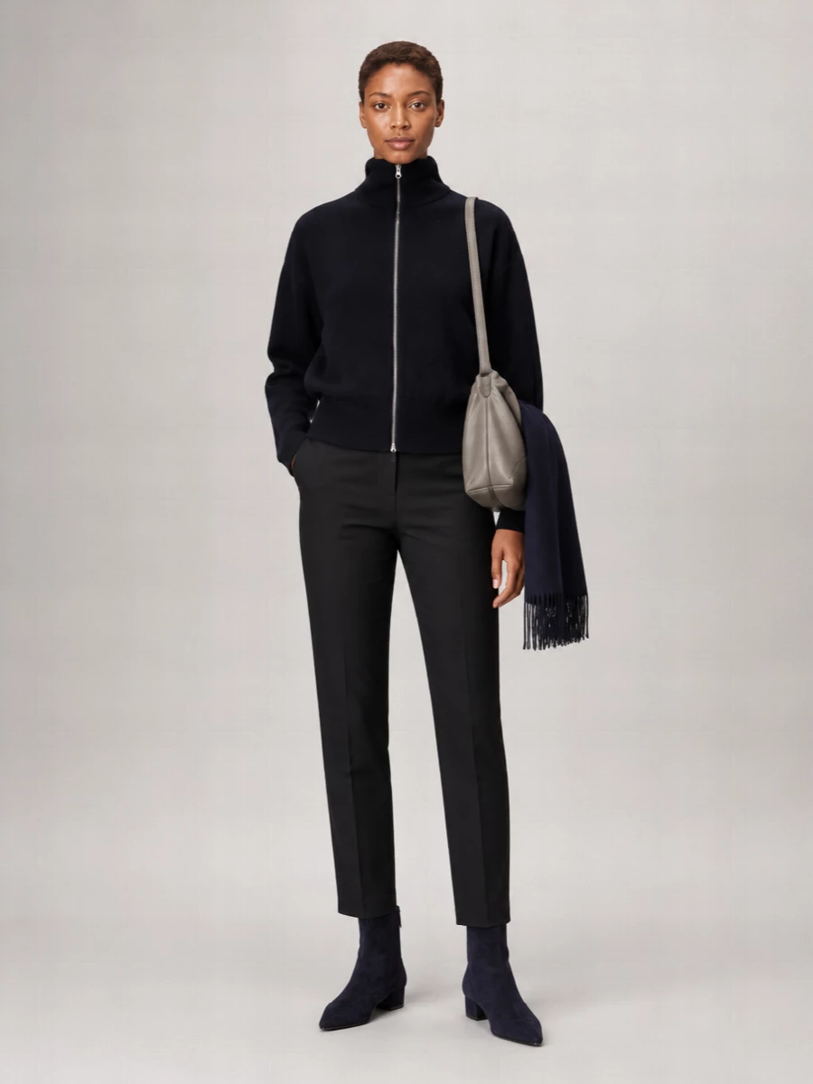 Deep navy and black sit together here in an unfussy, modern way, with the tailored trouser sharpening the cocooned jumper. Pointed navy boots and a soft grey shoulder bag keep everything streamlined, so the colour shifts feel deliberate rather than busy. It is a quietly confident winter outfit that moves easily from a long workday to a low-key dinner.