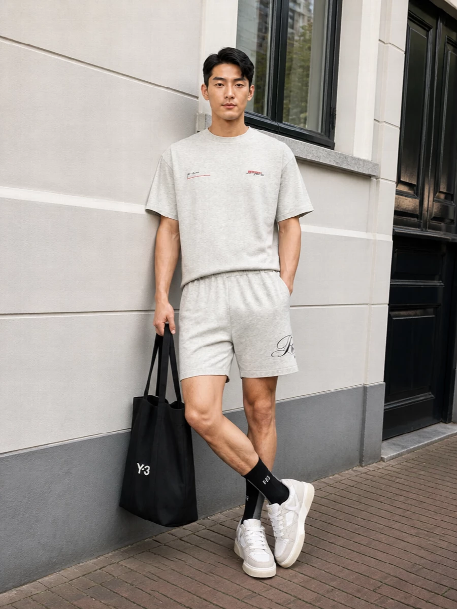 A tonal grey Represent tee and matching shorts create a calm, city-ready base that feels clean rather than gym-bound. Soft neutral sneakers keep the palette tight, while the black tote and graphic socks inject just enough contrast and attitude without breaking the minimalist rhythm.