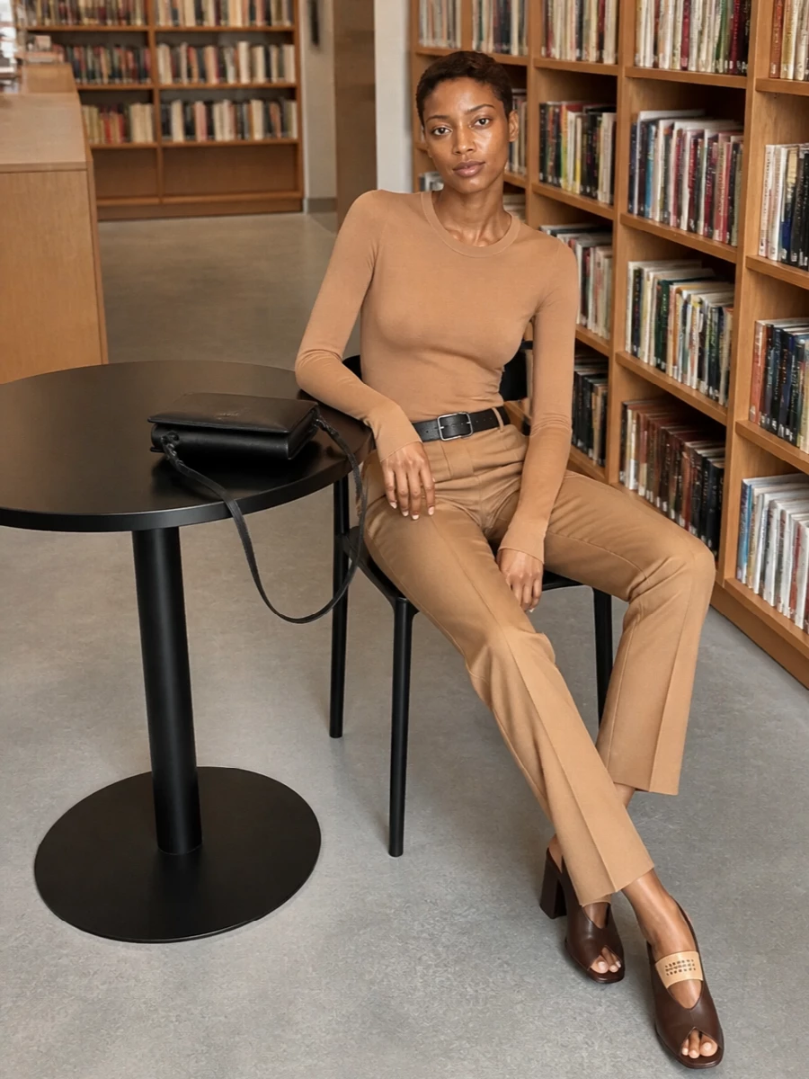 Camel on camel creates a long, uninterrupted line, with the nude bodysuit and tailored trouser reading as one quiet, precise column. A chocolate slingback and black belt with a slim black shoulder bag bring just enough contrast to ground the neutrals without disturbing the minimalist mood. The result is clean, polished and understated, ideal for days that move from studio to dinner with no change required.