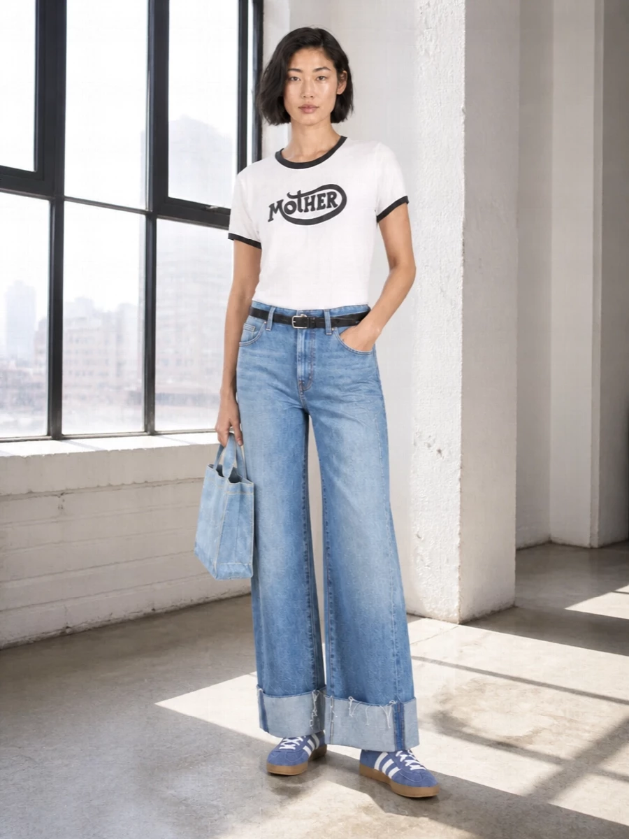 Relaxed wide-leg Mother denim sets up an easy streetwear base, sharpened by the crisp logo ringer tee and a slim black belt to define the waist. Soft blue Adidas retro sneakers and the compact Acne Studios tote keep the palette light and graphic, so the volume at the hem feels intentional rather than heavy. It is an off-duty uniform that reads playful and pulled together in equal measure.