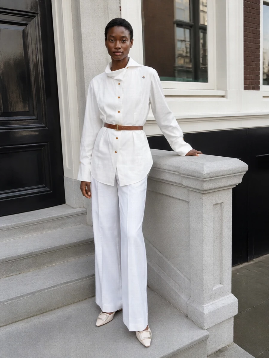 A longline Vivienne Westwood shirt meets Bottega Veneta’s column of white for a monochrome take on tailored ease that feels precise without looking stiff. Cream Roger Vivier flats keep the line elongated yet comfortable, while a structured Prada top-handle and a slim tan belt introduce just enough warm contrast to stop the palette from feeling clinical. The result is quietly assertive city polish that works from working lunch to late dinner with a simple change of lipstick.