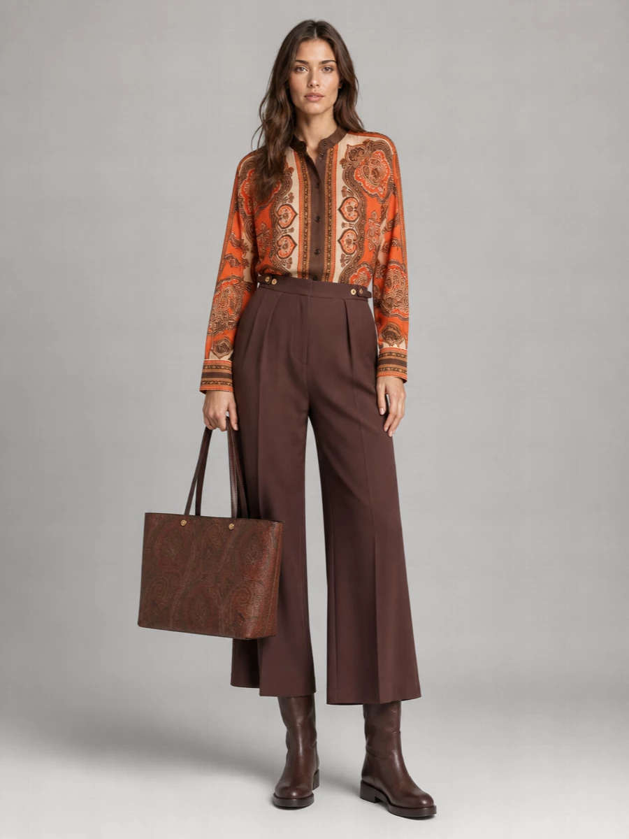 This pairing leans into warm, tapestry tones by letting the paisley shirt and Etro tote share the spotlight against clean, chocolate tailoring. The high-waisted wide-leg trouser and straight knee boot create a long, relaxed column that feels boho yet office-ready, while the rich browns and rusts stay within a refined, quiet luxury palette. Opting for separates instead of a dress keeps the prints intentional rather than overwhelming, and makes the outfit versatile from day through dinner.