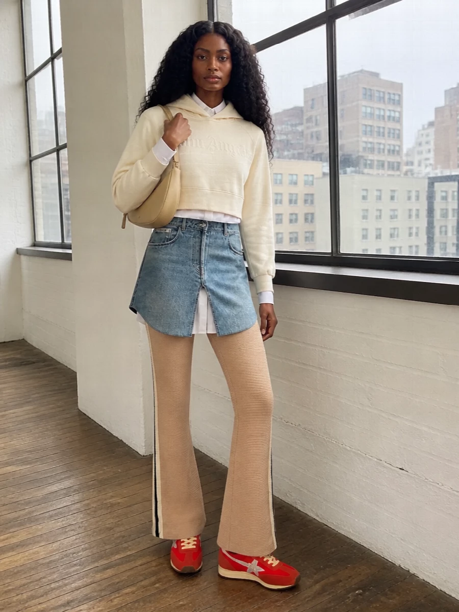 Cropped Palm Angels and flared knit track pants in warm neutrals frame the red retro runners so they feel intentional rather than loud. The high rise and slight flare keep the proportions long and lean, while the butter-beige Ferragamo hobo adds just enough polish for coffee runs, travel days or off-duty city time without fighting the sport energy of the shoe.