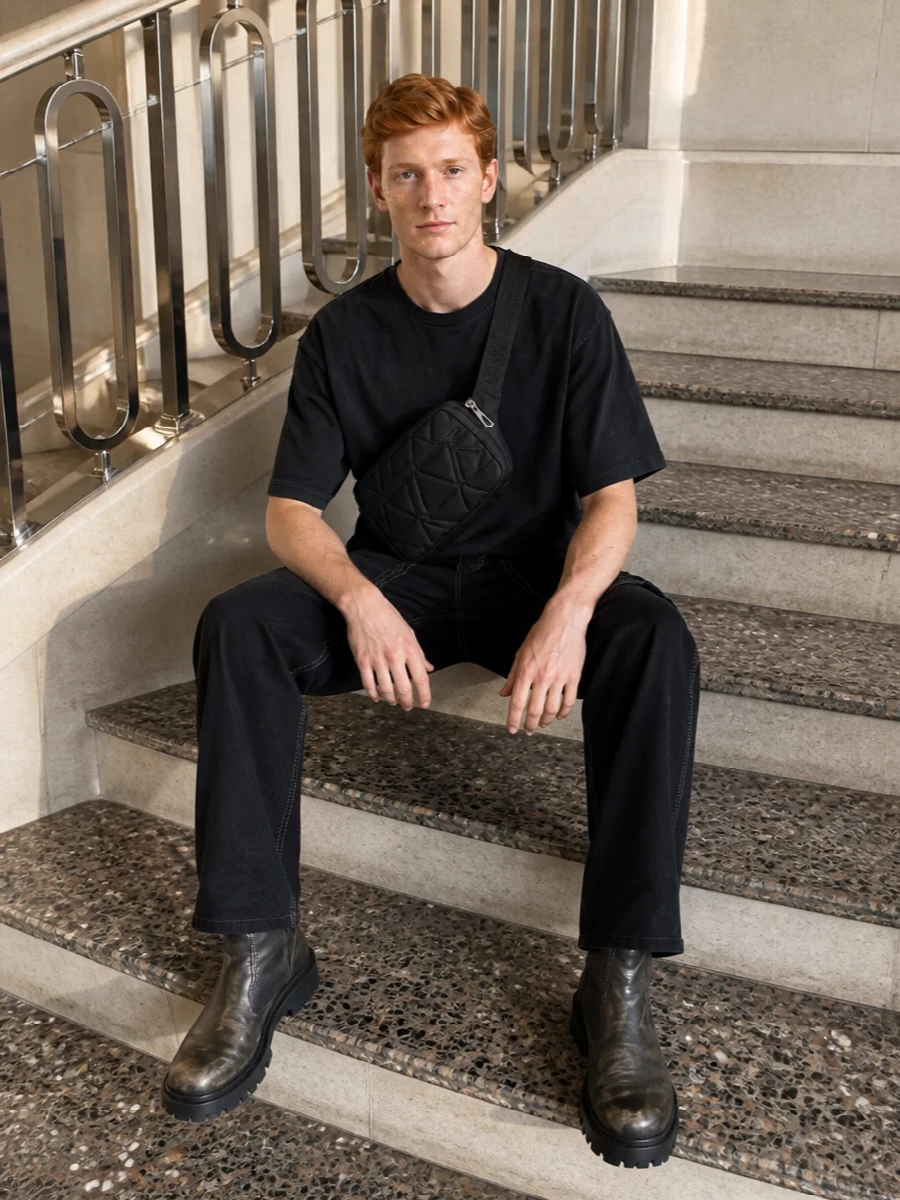 A washed-black boxy tee and loose black contrast-stitch cargos frame the Balenciaga boots in a stark, utilitarian palette. The silhouette stays relaxed up top and straight through the leg, letting the brutal lug sole and distressed leather carry the attitude. A quilted belt bag in black ties it together with just enough hardware to echo the boots without breaking the monochrome mood.