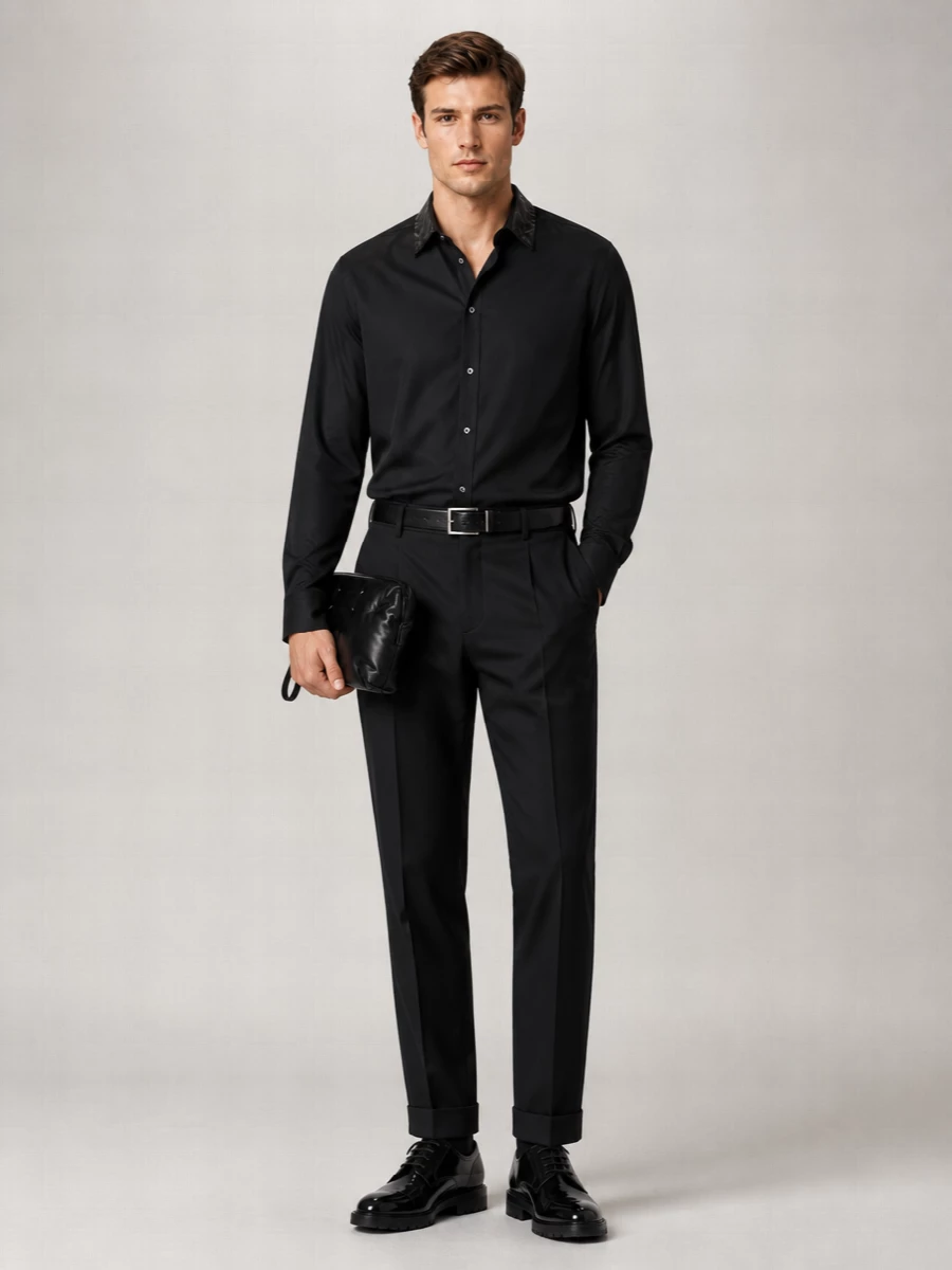 A precise black-on-black Margiela evening ensemble that lets cut, sheen and proportion do the talking. The pleated, cuffed trouser and fluid shirt create a long, clean line, grounded by a high-shine lug-soled derby for a controlled, contemporary formality. A padded clutch and slim silver-buckled belt add just enough texture and metal to keep the finish deliberate without noise.