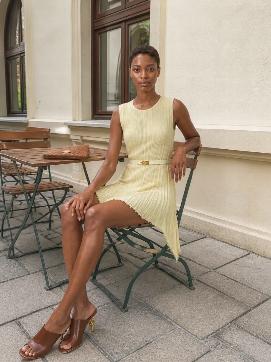I’ve taken the dress route to let the butter-yellow belt sit seamlessly against a matching pale Bottega pleated mini, creating a single, quiet column of color. Sculptural chocolate mules and a caramel intrecciato clutch introduce depth and warmth while keeping the palette tightly neutral and the silhouette clean. The result is a quietly luxurious evening ensemble where the belt reads as considered jewelry rather than an afterthought.