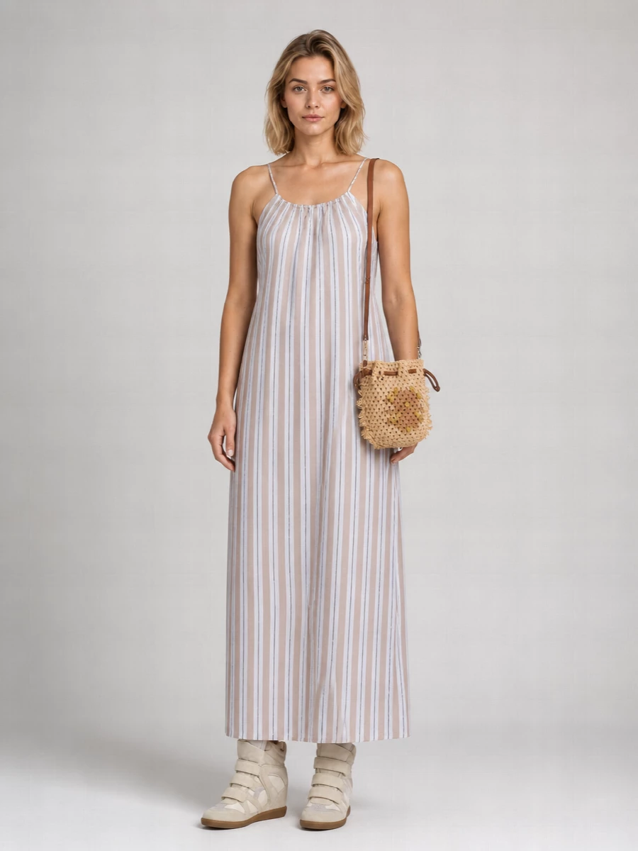 This pairing takes the wedge sneaker into a sun-washed, boho direction with a striped maxi that feels easy through the body but visually elongated and clean. The neutral column lets the high-top shape stay graphic without fighting it, while the woven bucket bag adds just enough texture and movement for a relaxed, summer-in-the-city mood. I chose the dress route here because its long, fluid line works better with the concealed wedge height than a trouser break would, keeping everything light and leggy instead of bulky at the ankle.