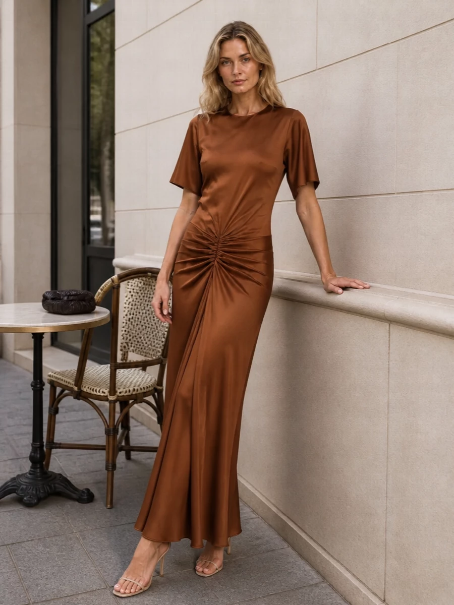 Copper satin and soft champagne tones create a warm, luminous evening story that still feels restrained. The slim stiletto and structured clutch keep the ruched maxi clean and elongated, with no visual noise. This is a quietly confident option for summer dinners or city weddings where you want polish without overt sparkle.