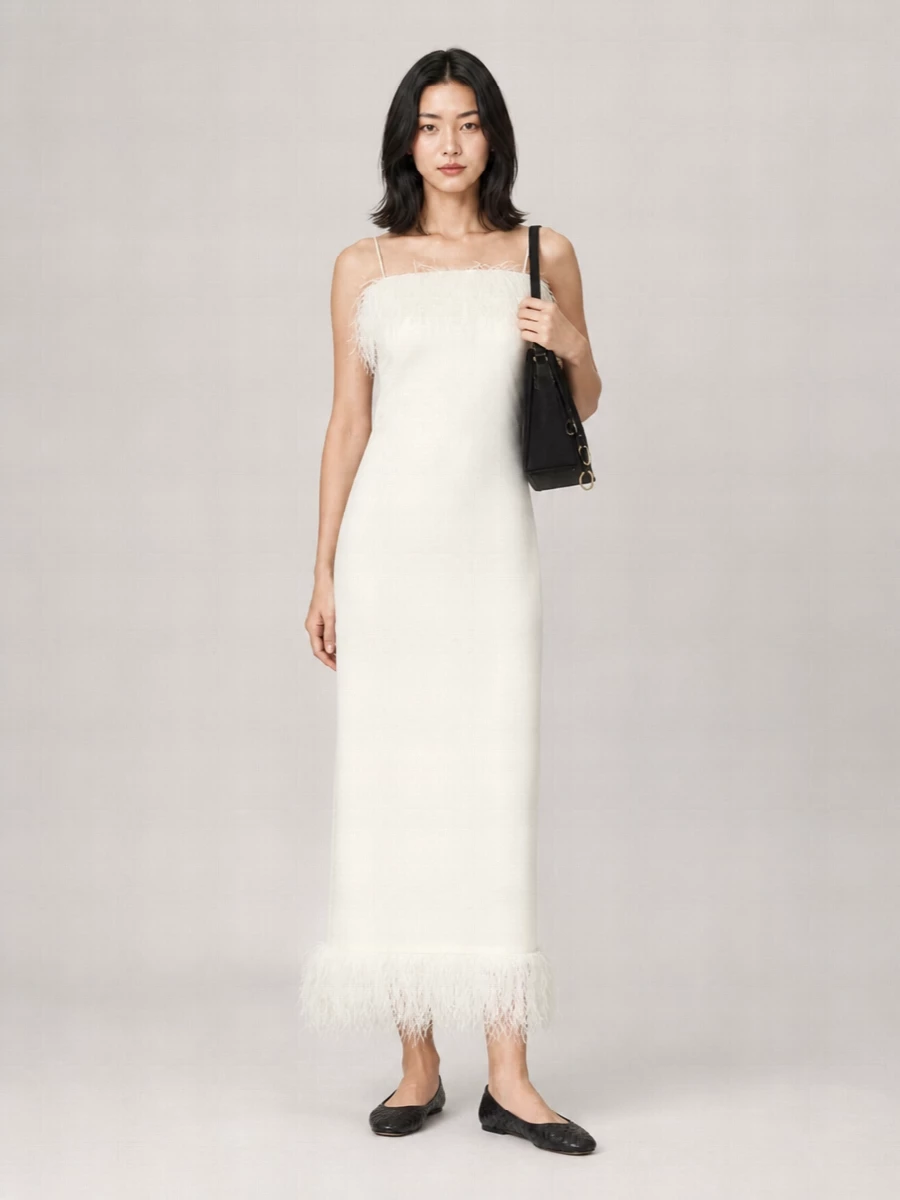 An ivory feather-trim slip dress paired with charcoal intrecciato flats creates a soft, elongated line that feels romantic yet quietly precise. The black Alaïa shoulder bag grounds the light tones and subtly ties into the shoes, keeping the mood polished without heaviness. Opting for the dress route keeps the story clean and modern, letting texture and cut do the work instead of extra separates.