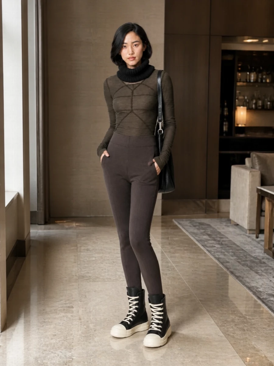 A tonal knit base in shadowy browns keeps everything close to the body, so the seamwork and proportion become the focus. Black, sculptural accessories and sneakers add just enough weight and contrast, keeping the palette moody while the attitude stays off-duty and urban. It feels like winter loungewear sharpened for the street rather than the sofa.