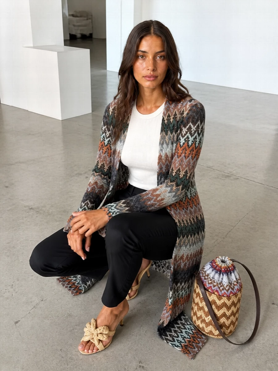 The Missoni duster becomes the hero, its sun-faded chevrons grounded by straw-beige raffia mules and a compact woven bucket bag that echo its ease without shouting. Neutral, tactile accessories keep the palette calm and quietly polished, ideal over an ivory slip or slim ecru trouser when you want movement and softness with just enough structure. The result is relaxed boho energy translated into something you can easily wear to city dinners, seaside terraces or long garden parties.