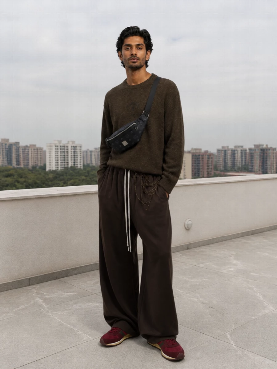 Gucci’s burgundy runners ground a moody, directional streetwear set, picking up the forest tones in the Mm6 knit and sitting warm against the deep chocolate Rick trousers. The ultra-wide leg and straight, slightly subversive top create that relaxed, stacked proportion, while the black MCM belt bag keeps things hands free and graphic without breaking the rich autumn palette. It is an off-duty city uniform that reads luxurious but still feels ready for movement.