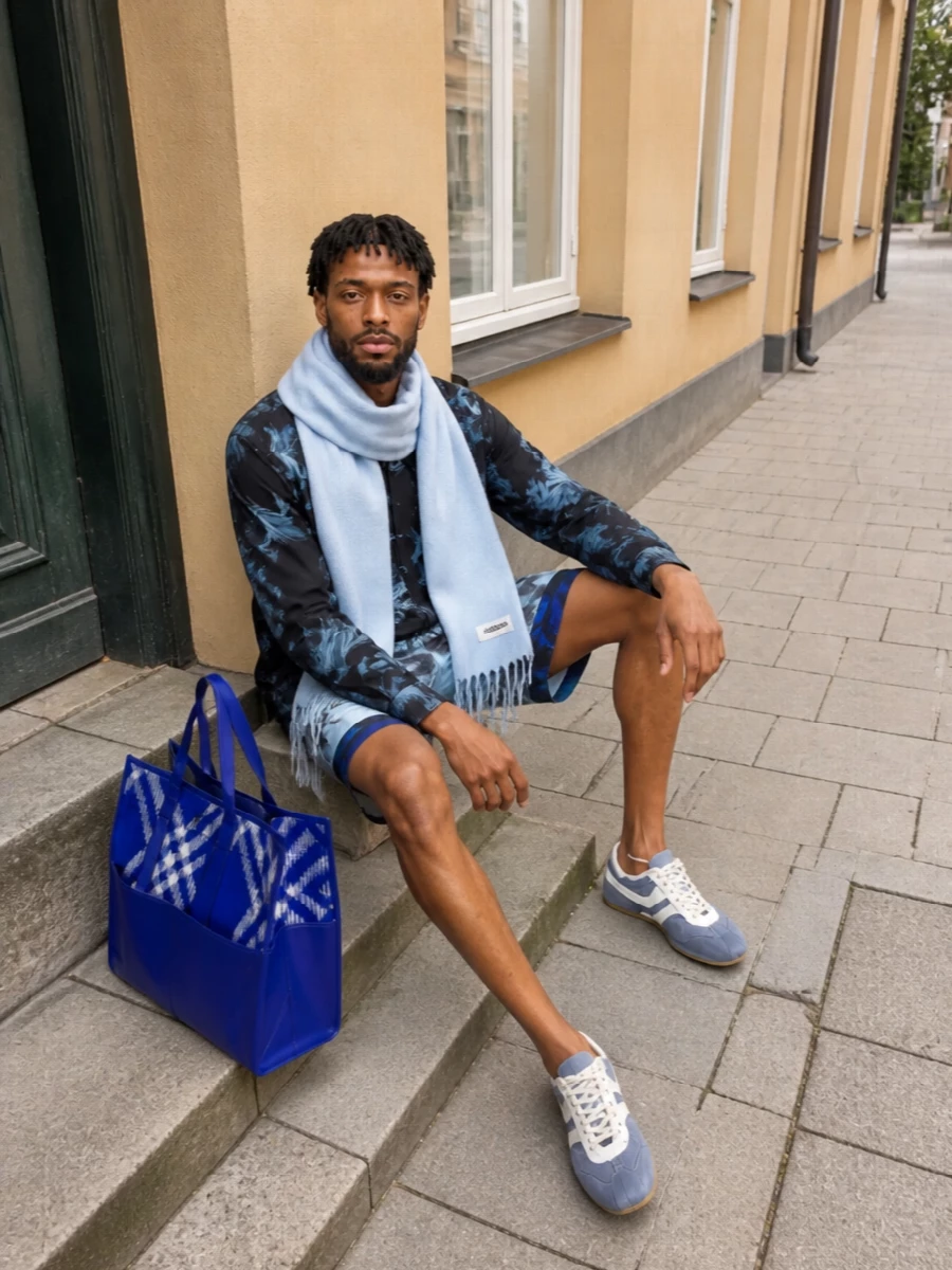 Inky florals stay the story here, with the black-and-ice Dries shirt echoing the shorts’ painterly print for a tight, graphic pairing. Slate runners and the cobalt tote keep it firmly in a sport-leaning city mood, while the pale blue scarf cools everything down and nods quietly to the swim’s ice base.