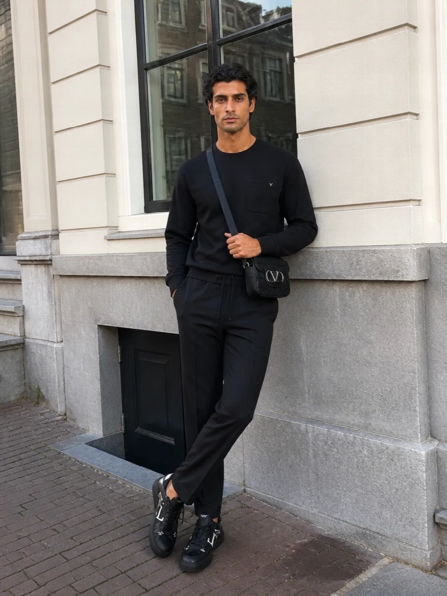 A monochrome Valentino Garavani uniform that reads clean, graphic and quietly expensive. The pocketed sweatshirt and straight-leg drawstring trouser sit in that sweet spot between track and tailoring, keeping the sneakers firmly in a city-ready context. The compact crossbody repeats the V detail without shouting, so the whole outfit feels composed and modern from café runs to late dinners.