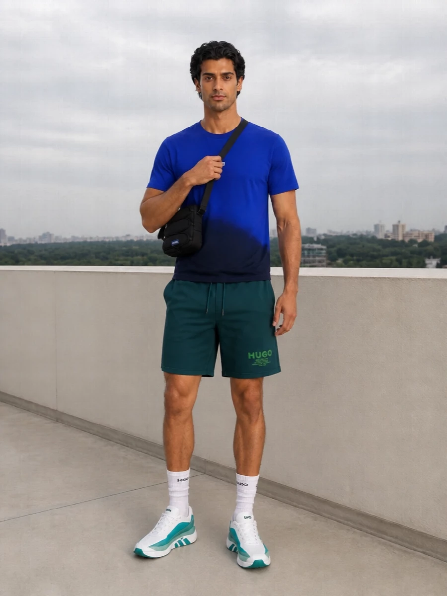 Deep teal shorts meet a cobalt dip-dye tee for a sharp, color-blocked pool-to-city outfit that still feels easy and relaxed. White-and-teal runners keep it technical and fresh, while the compact black crossbody and discreet belt add just enough structure without diluting the sporty attitude.