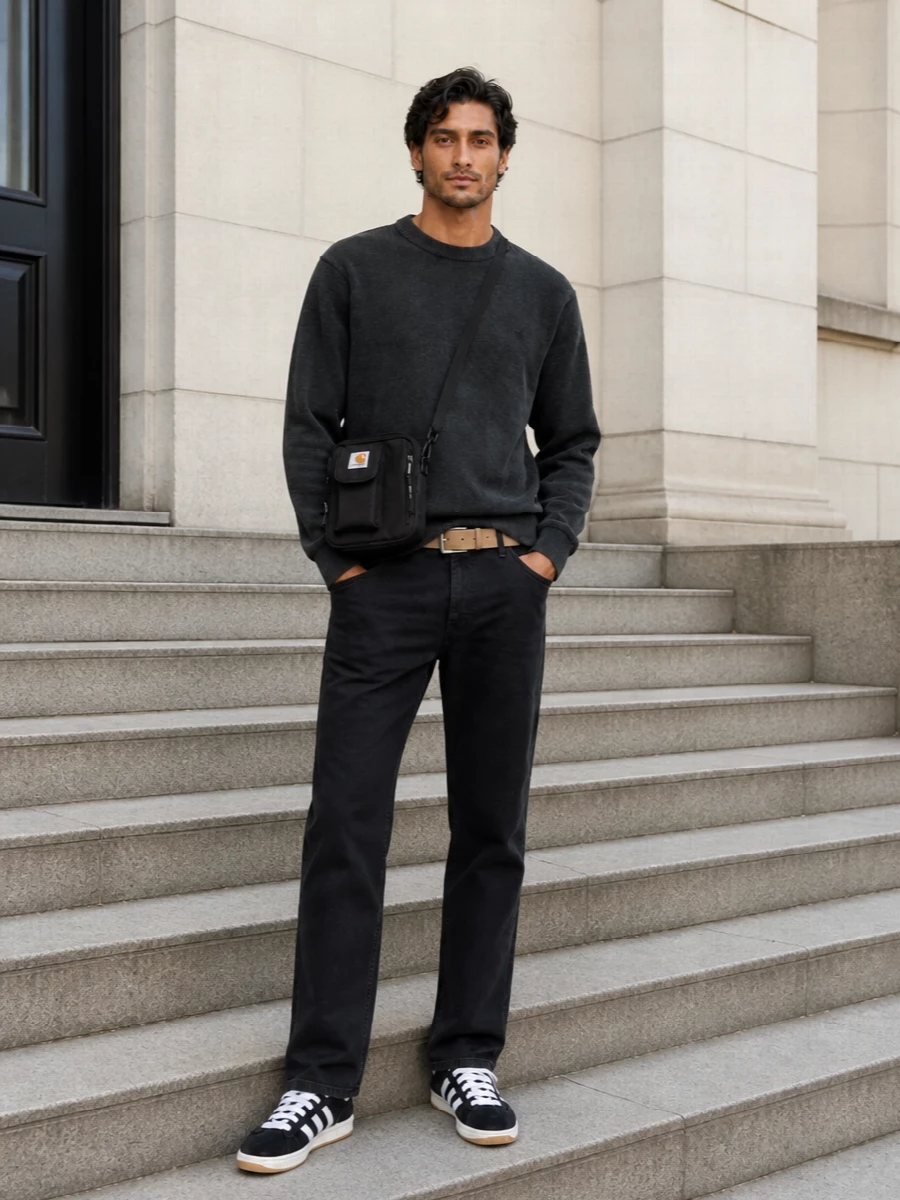 Faded black work pants and a charcoal crew frame a low-key, monochrome Carhartt story with a relaxed straight silhouette. Black suede Campus sneakers and a compact crossbody keep it in a skate-adjacent, city-ready lane, grounded and unfussy for daily wear.