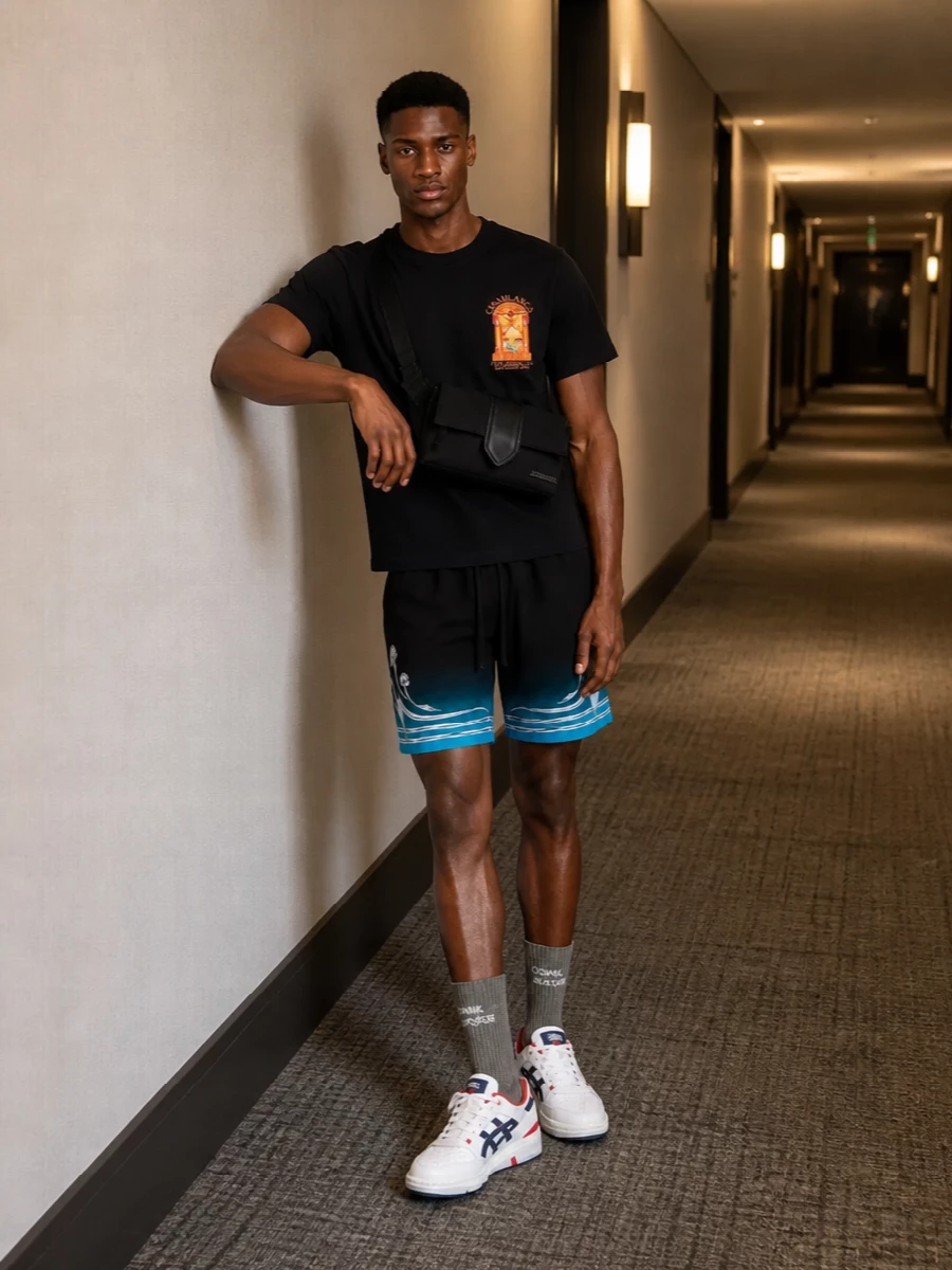 Graphic street-sport energy grounded in black and teal, this outfit lets the Casablanca tee and shorts carry the story while everything else stays clean and functional. White court sneakers sharpen the silhouette and echo the athletic mood, and a low-key belt bag plus logo socks keep it city-ready without crowding the print. It is relaxed but intentional, perfect for days when you want comfort with a strong point of view.