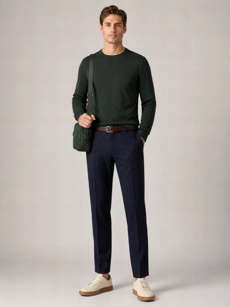 Dark forest green and navy create a calm, grounded palette, with the tailored drawstring trouser keeping the knit firmly in smart casual territory. Cream gum-sole sneakers and a dark brown belt warm the combination, while the structured forest-green crossbody adds a precise, modern finish without disturbing the clean lines.