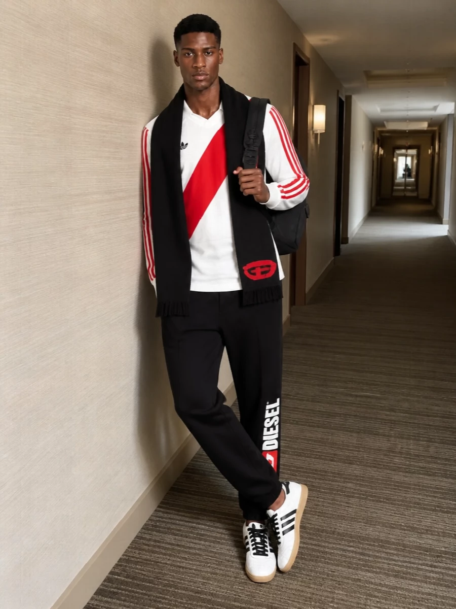 This outfit leans into retro football energy with a clean, graphic palette of white, black, and hits of red. Relaxed joggers and terrace sneakers keep it easy and mobile, while the sharp logo details and technical backpack give it a modern streetwear edge. It feels casual enough for weekend city moves but considered enough to read intentional, not lazy.