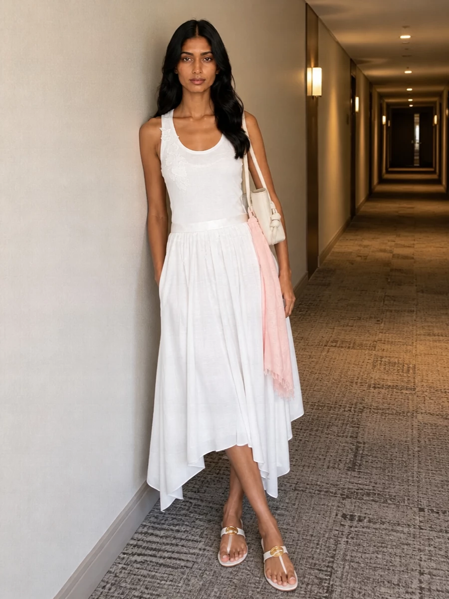 An all‑white story built around the floral‑detailed tank and a gauzy asymmetric midi skirt feels light, feminine and quietly relaxed. Sleek white flats keep it grounded and easy for warm days, while an ivory shoulder bag adds just enough structure to stay polished. A blush scarf brings a hint of color that still reads soft and romantic against the clean palette.
