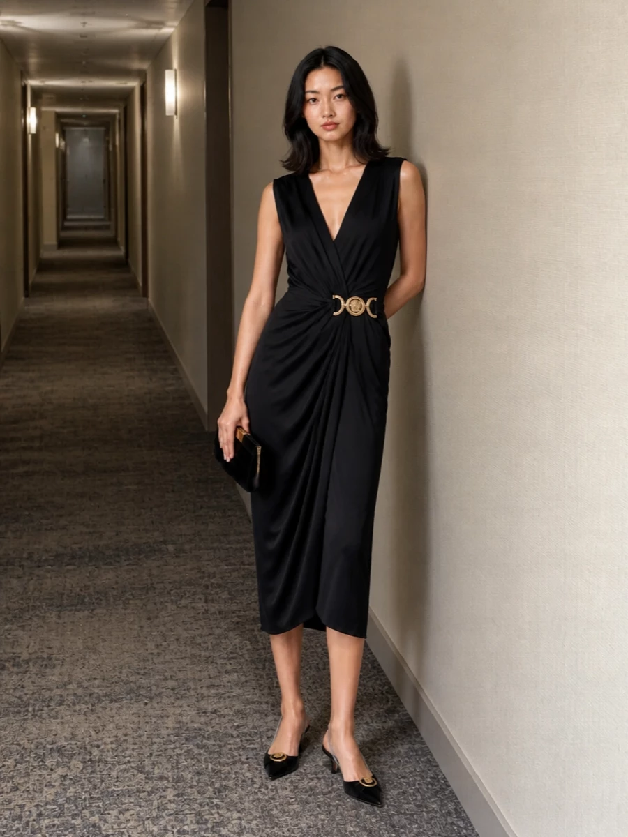 This is cocktail dressing with a precise, sculpted edge: the black draped Versace dress anchored by a low, sharp slingback keeps everything long, lean and quietly dramatic. A velvet clutch and optional cummerbund-style belt deepen the texture play while still reading ultra-polished, so the gold accents feel intentional rather than loud. It is made for late dinners, gallery openings and black-tie-adjacent nights where you want clear Versace attitude with a very considered finish.