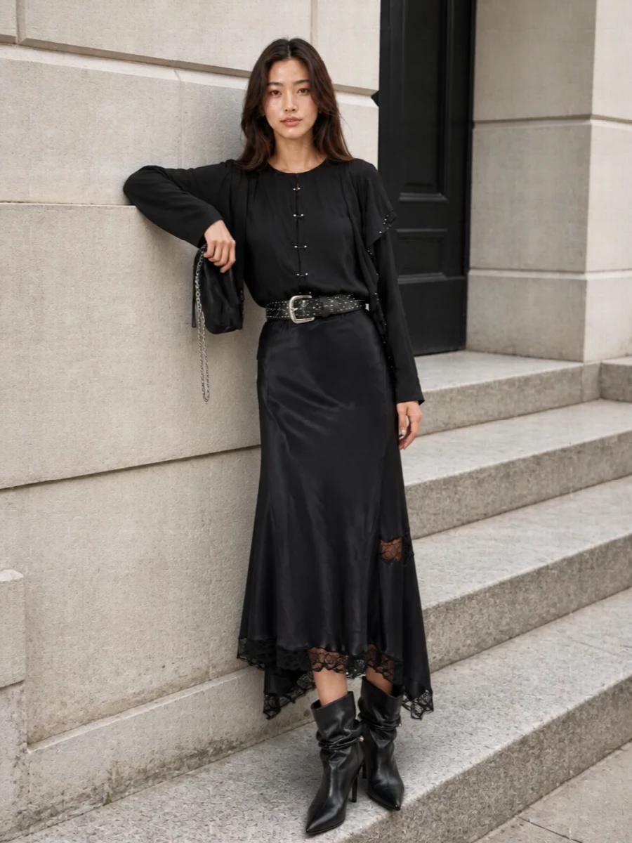 A dark, romantic Isabel Marant evening ensemble built around fluid movement and subtle shine. The asymmetric satin and lace skirt extends the blouse into a long, inky column, cinched with a studded waist for definition. Slouchy stiletto boots and a ruched chain-strap clutch keep the mood sultry and Parisian for dinners, art openings, or low-lit bars.