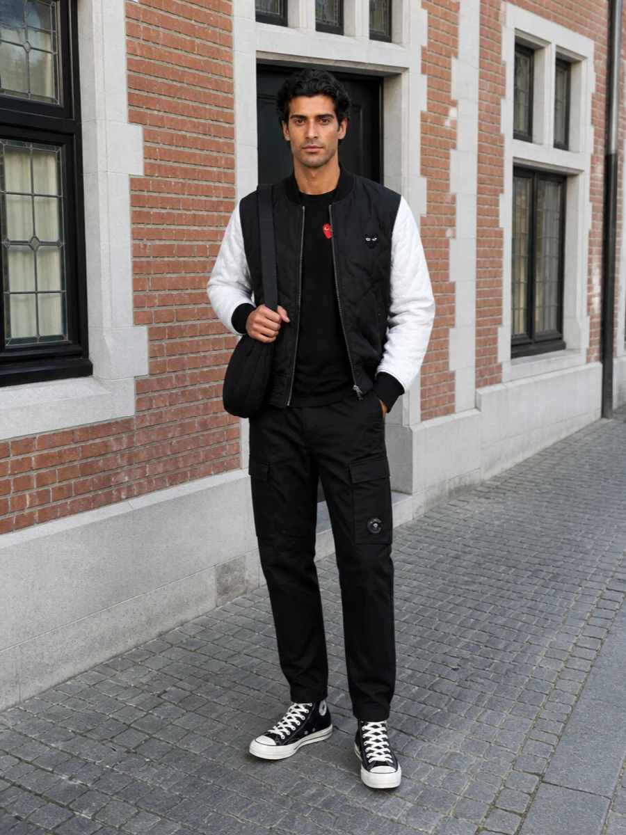 All in on graphic Japanese street, but kept sharp and monochrome. The padded Play bomber sits over a black heart-logo long sleeve and crisp C.P. cargos, finished with matching hi-tops and a quilted sling. It is an easy city uniform that feels intentional without getting loud about it.