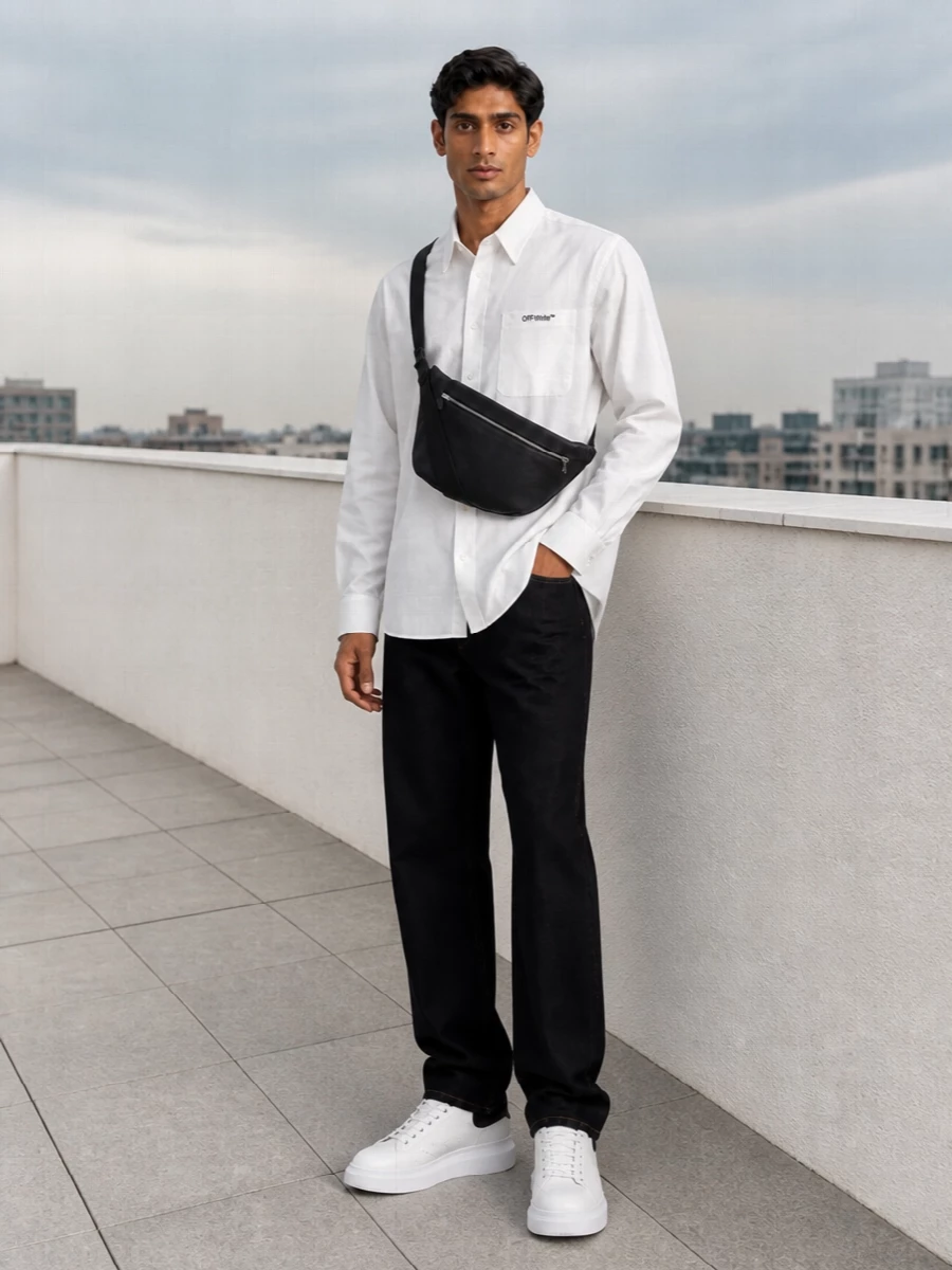 A crisp white shirt against inky black denim lets the McQueen sneakers do quiet work, keeping the whole palette high-contrast and clean. The proportions stay easy and straight, so the chunky sole feels intentional rather than heavy. A curved black sling ties it together with a subtle street accent that still reads refined in the city.