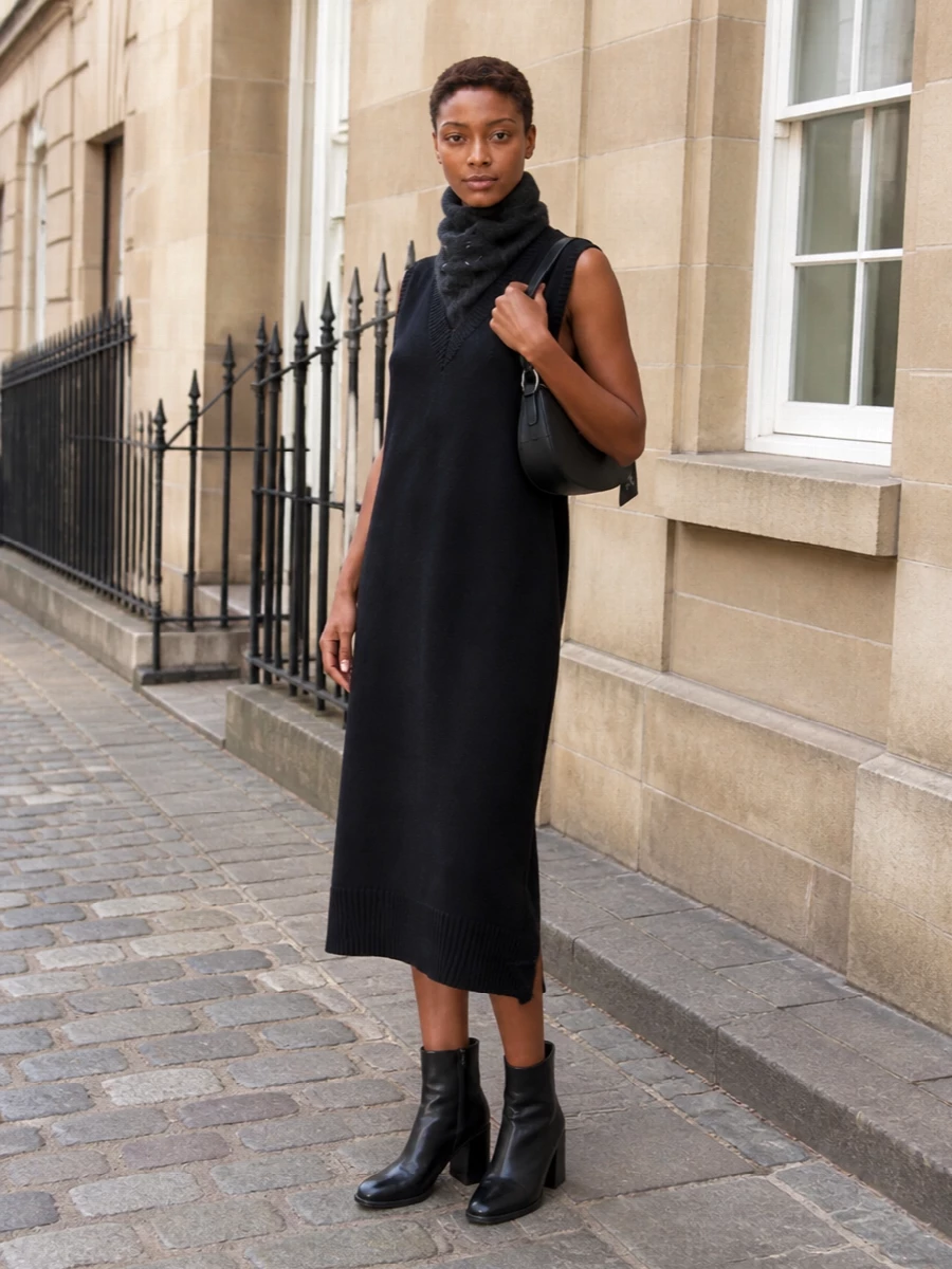 A black knitted column paired with clean Margiela ankle boots and a compact crescent bag creates a quiet, city-ready uniform in deep, uninterrupted lines. The close charcoal neck scarf adds just enough contrast and warmth while preserving the minimalist, cocooned mood. It is relaxed but considered, ideal for days that move from errands to an understated dinner.