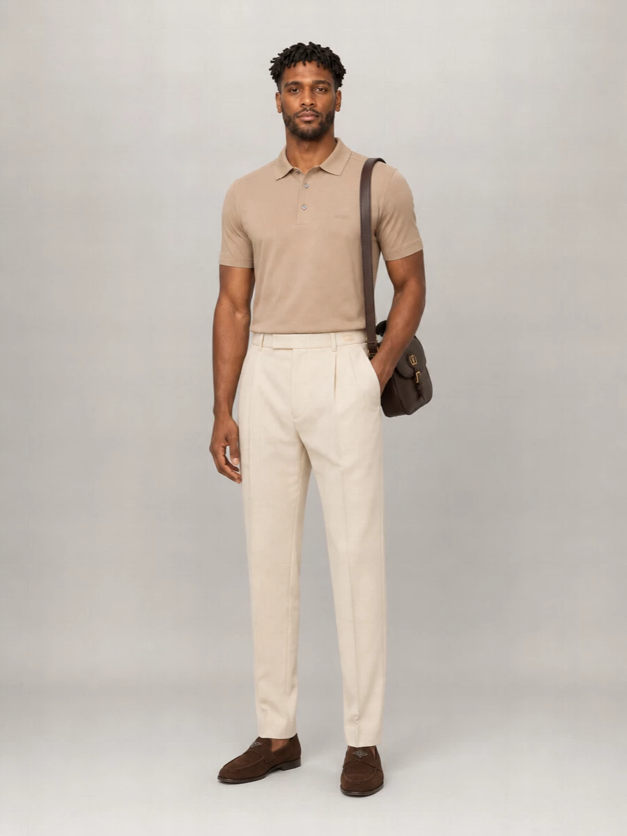 A camel knit polo and light beige pleated trouser frame the brown suede loafer in a calm, tonal palette that reads quietly refined for city days. The soft tailoring and relaxed polo keep it on the right side of casual, while the rich leather shoulder bag adds just enough structure and depth. It is an easy warm-weather uniform that moves from coffee meetings to dinner without a change of shoe.