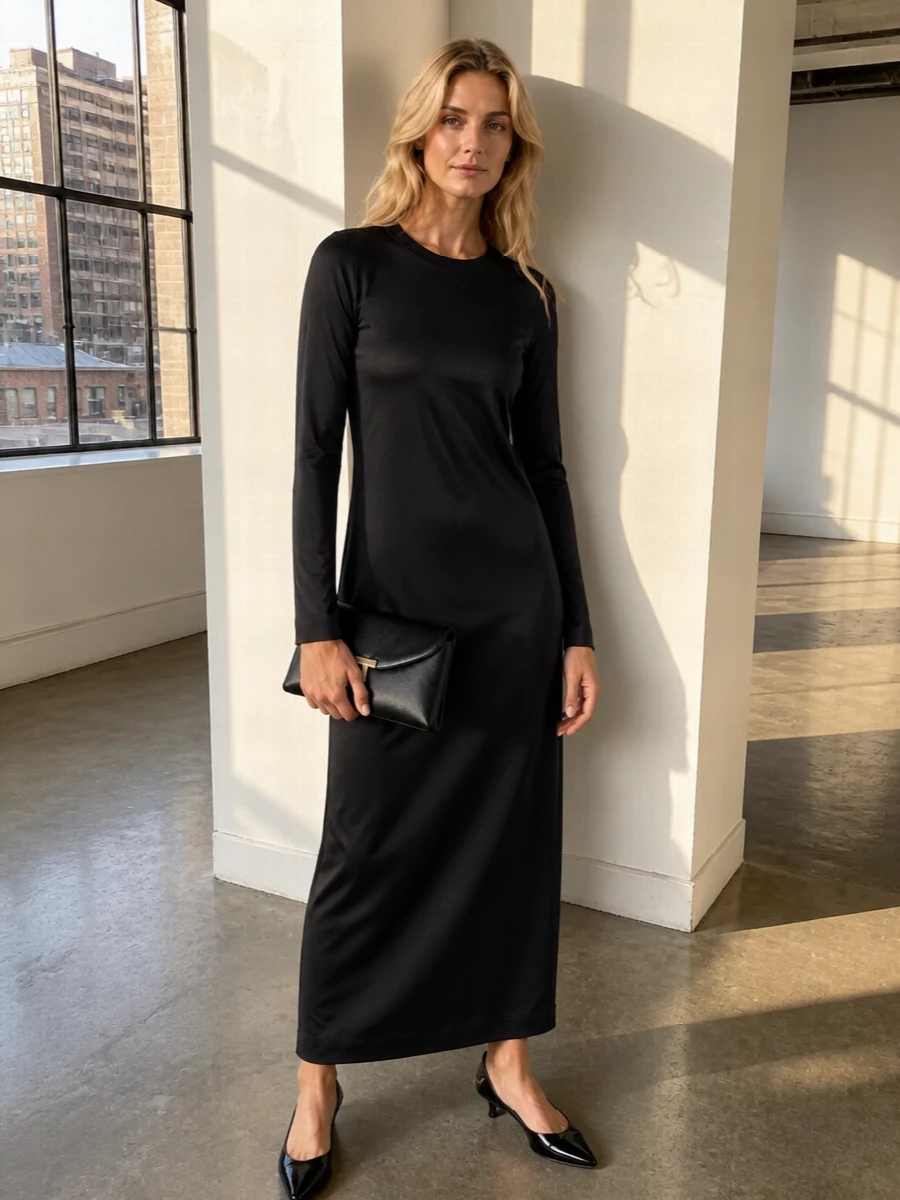 This is a pure black evening composition: a fluid Totême satin column dress echoed by the structured envelope clutch and discreet gold touches. The Tod’s patent kitten heels keep the line sharp yet wearable, so the whole outfit feels polished enough for formal dinners but relaxed enough for a late gallery tour. Choosing the dress route rather than separates keeps the silhouette long and uninterrupted, which best amplifies the clutch’s architectural presence.