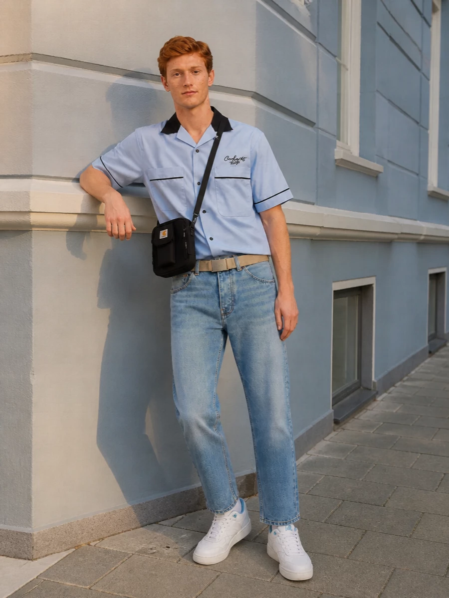 Pale blue bowling-shirt energy meets soft-faded cropped denim for a clean, skate-leaning take on preppy. White and ice-blue court sneakers keep it fresh underfoot, while a compact black crossbody brings just enough workwear utility and a sand belt grounds the waist without shouting.