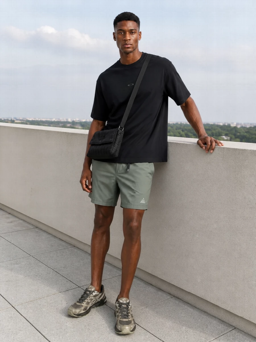 A relaxed black Oakley tee sits above sage ACG shorts for a clean, technical take on warm weather dressing. Muted Asics runners keep the palette low-key and ready for movement, while a padded C.P. Company crossbody adds just enough urban function without breaking the minimalist flow.