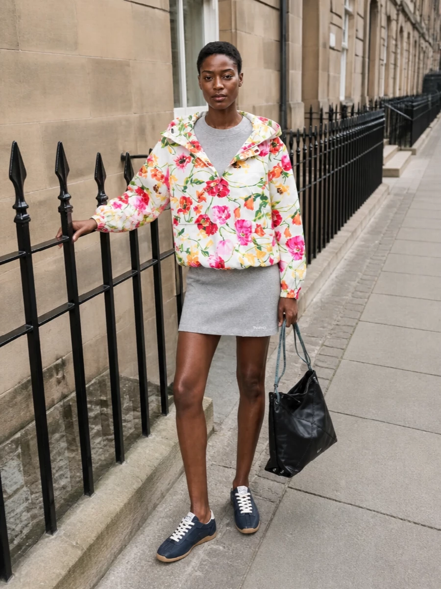 I am building around the dress path here, because the short sweatshirt mini creates one strong, streamlined base under the cropped Kenzo anorak rather than competing with it through a separate top and bottom. The result is a playful, floral-topped street outfit in a restrained grey and navy core, with coherent brand energy and proportions that keep the legs long and the upper half boldly graphic. Sneakers and a slouchy shoulder bag stay low-key but considered, so the outerwear can do the talking without the rest feeling underdressed.