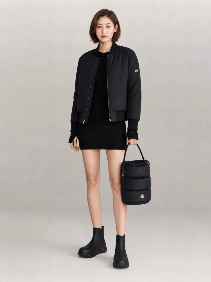 Anchoring this with the knit dress path keeps the outfit sharp and streamlined, so the bomber reads intentional rather than like loungewear layered over sweats. The ribbed black Sportmax mini, bulbous Moschino ankle boots and padded Moncler bucket bag create a monochrome, city-ready combination that feels sporty, minimal and winter-appropriate from day to low-key night.