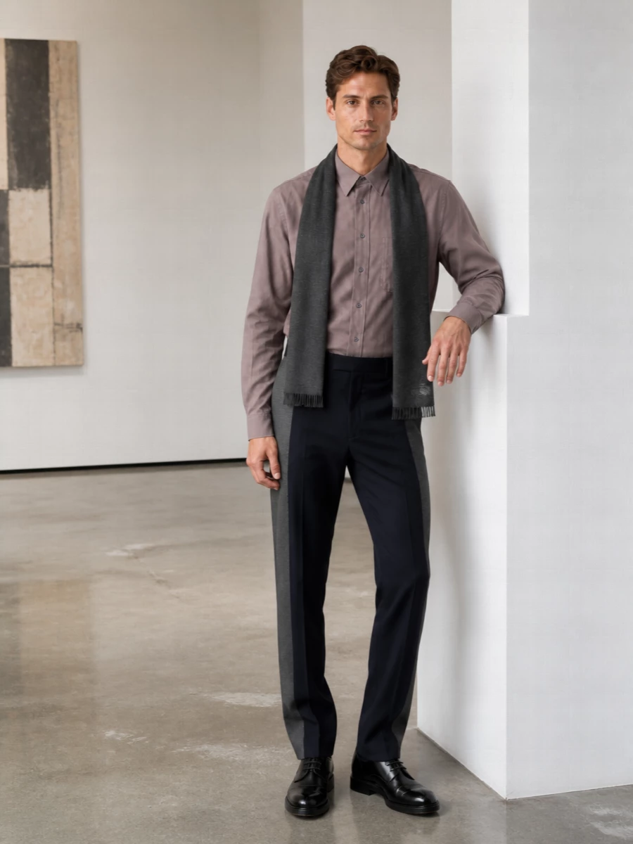 A taupe Margiela shirt meets precise two-tone tailoring for a calm, intellectual take on city dressing. Sleek black derbies and a padded briefcase keep the line sharp but unfussy, while a charcoal scarf quietly softens the formality for day-to-night wear.